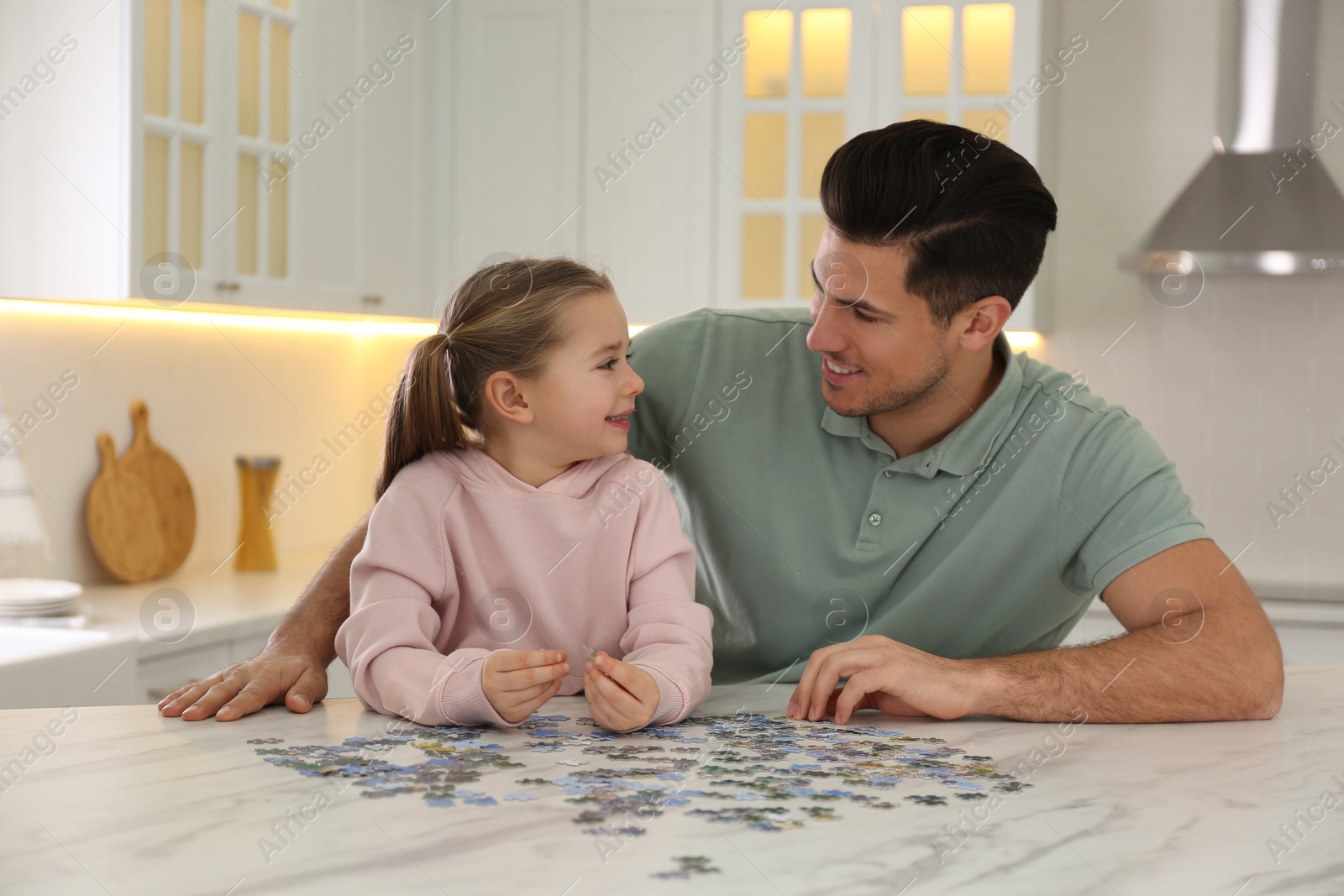 Photo of Man and his little daughter playing with puzzles at home