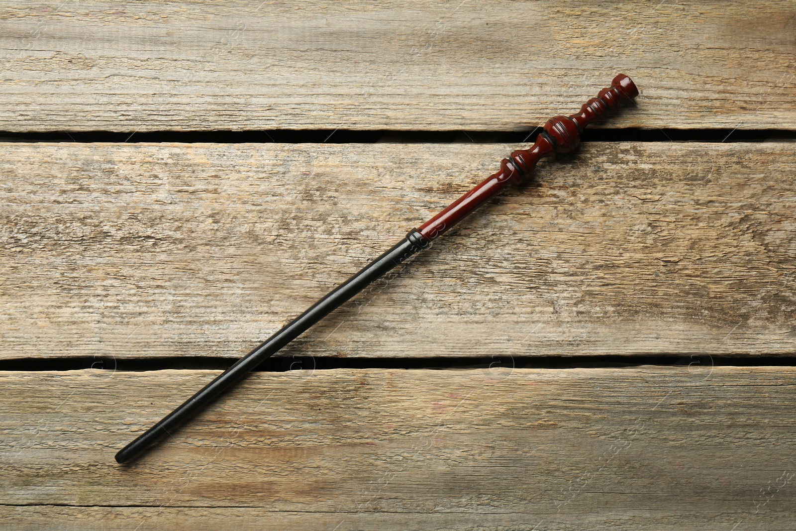 Photo of One old magic wand on wooden table, top view