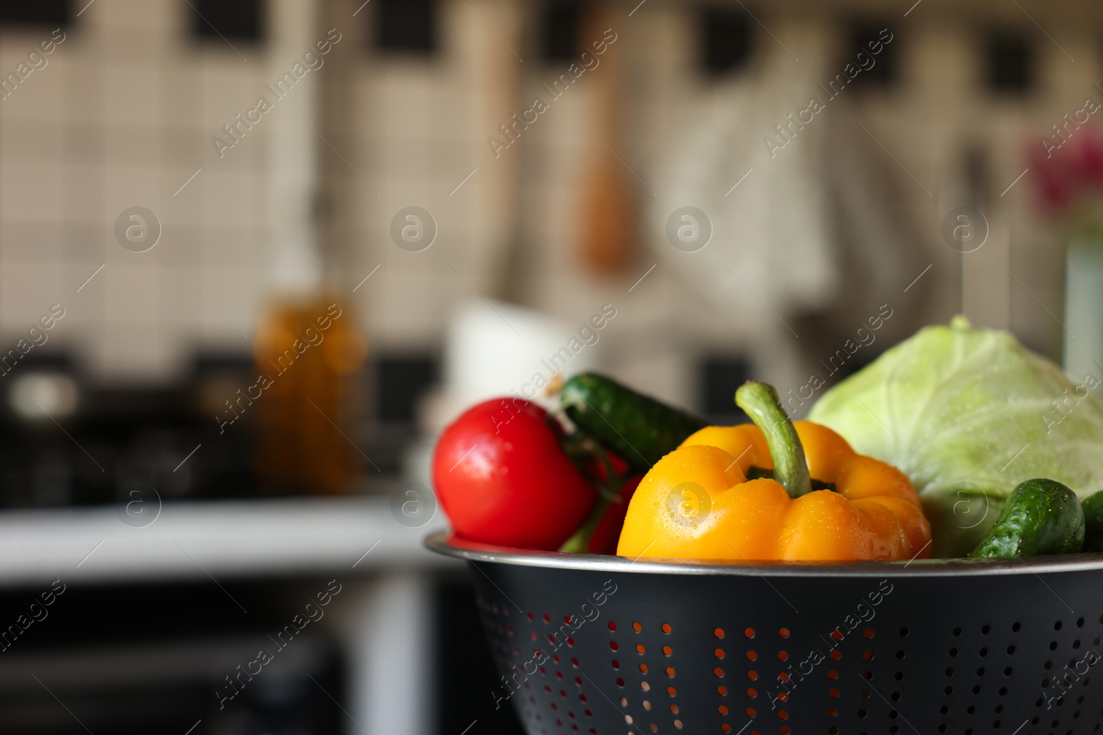 Photo of Metal colander with different wet vegetables on table, closeup. Space for text