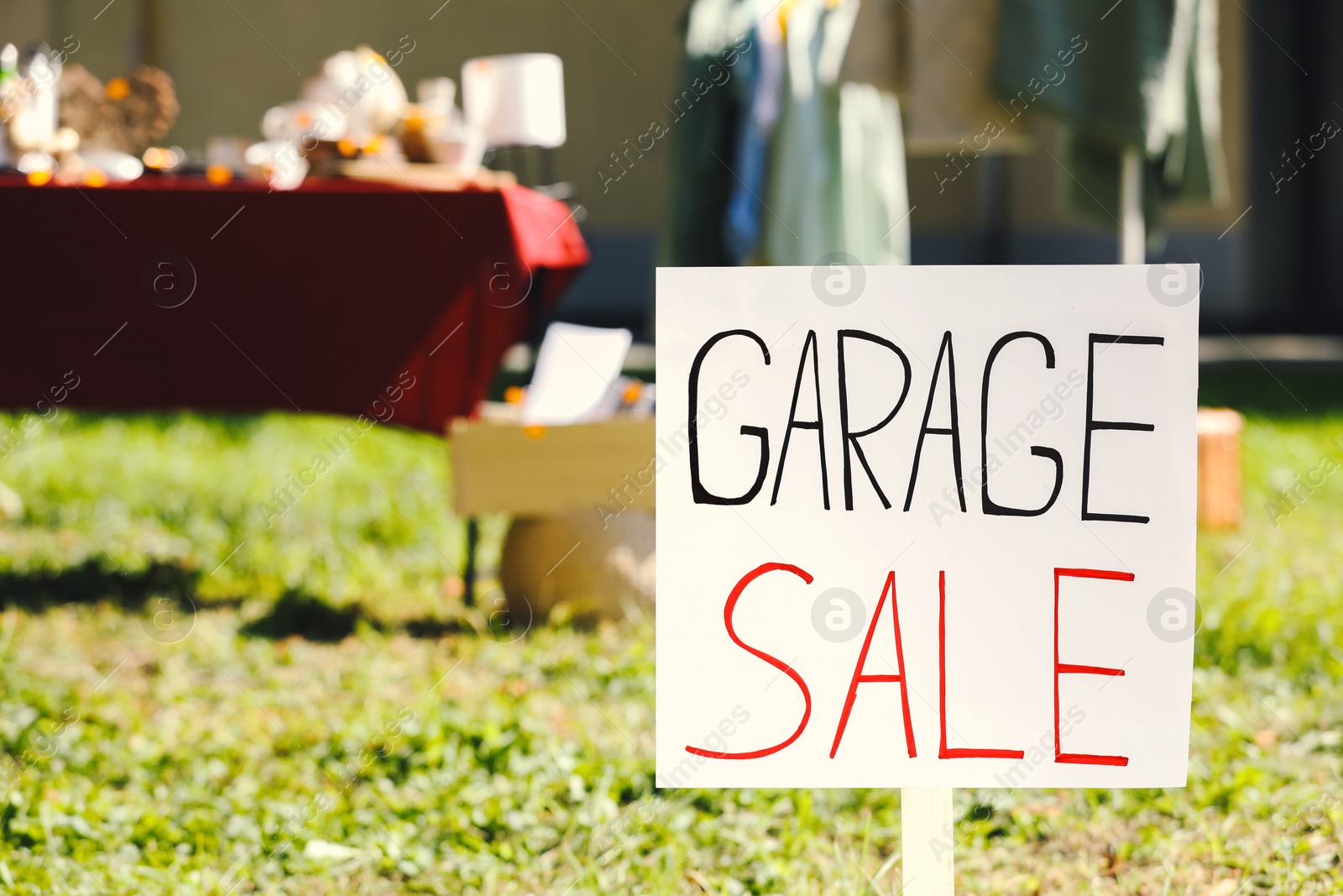 Photo of Sign Garage sale written on cardboard in yard, closeup. Space for text