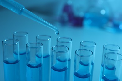 Photo of Dripping reagent into test tube with blue liquid, closeup. Laboratory analysis