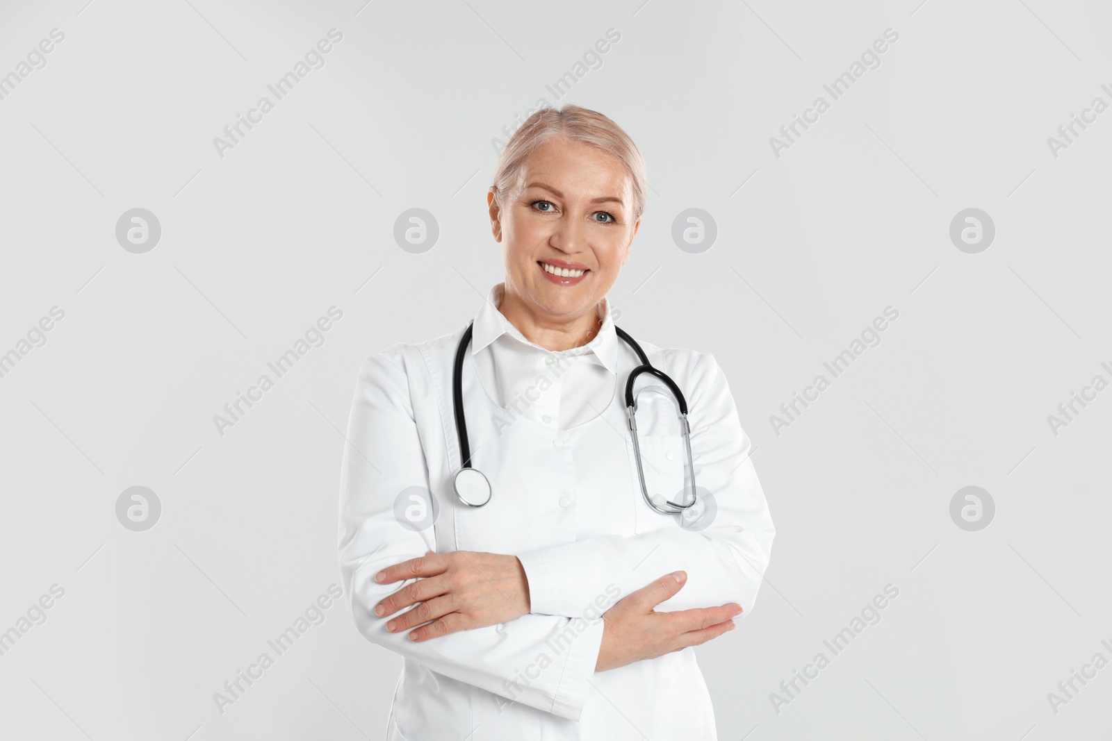 Photo of Portrait of mature doctor with stethoscope on light grey background