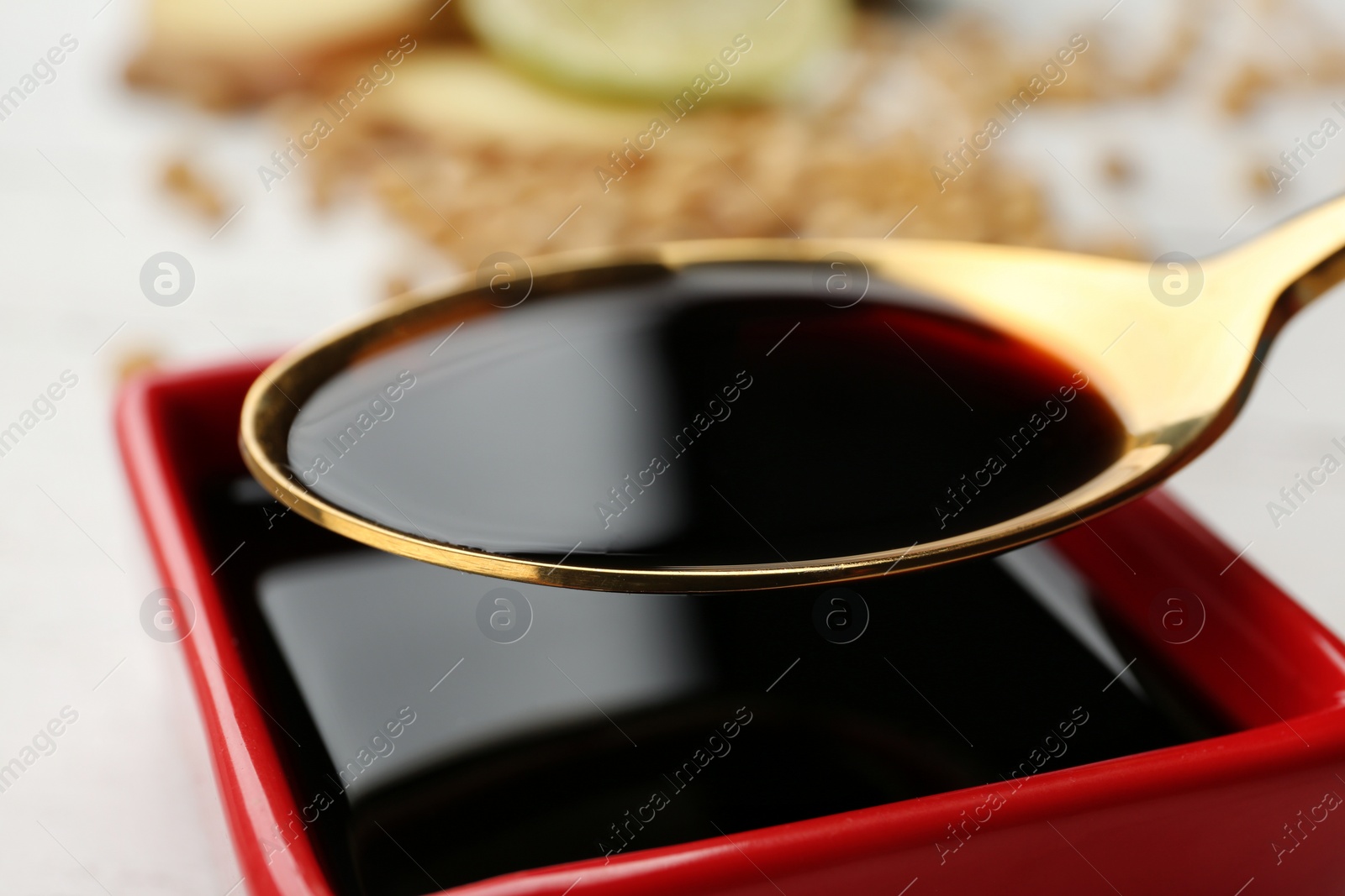 Photo of Spoon with soy sauce over dish, closeup