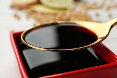 Photo of Spoon with soy sauce over dish, closeup