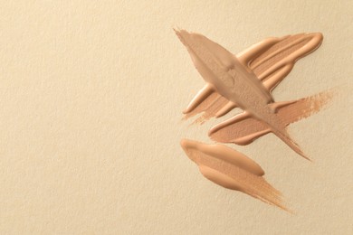 Photo of Samples of liquid skin foundations on beige background, top view. Space for text