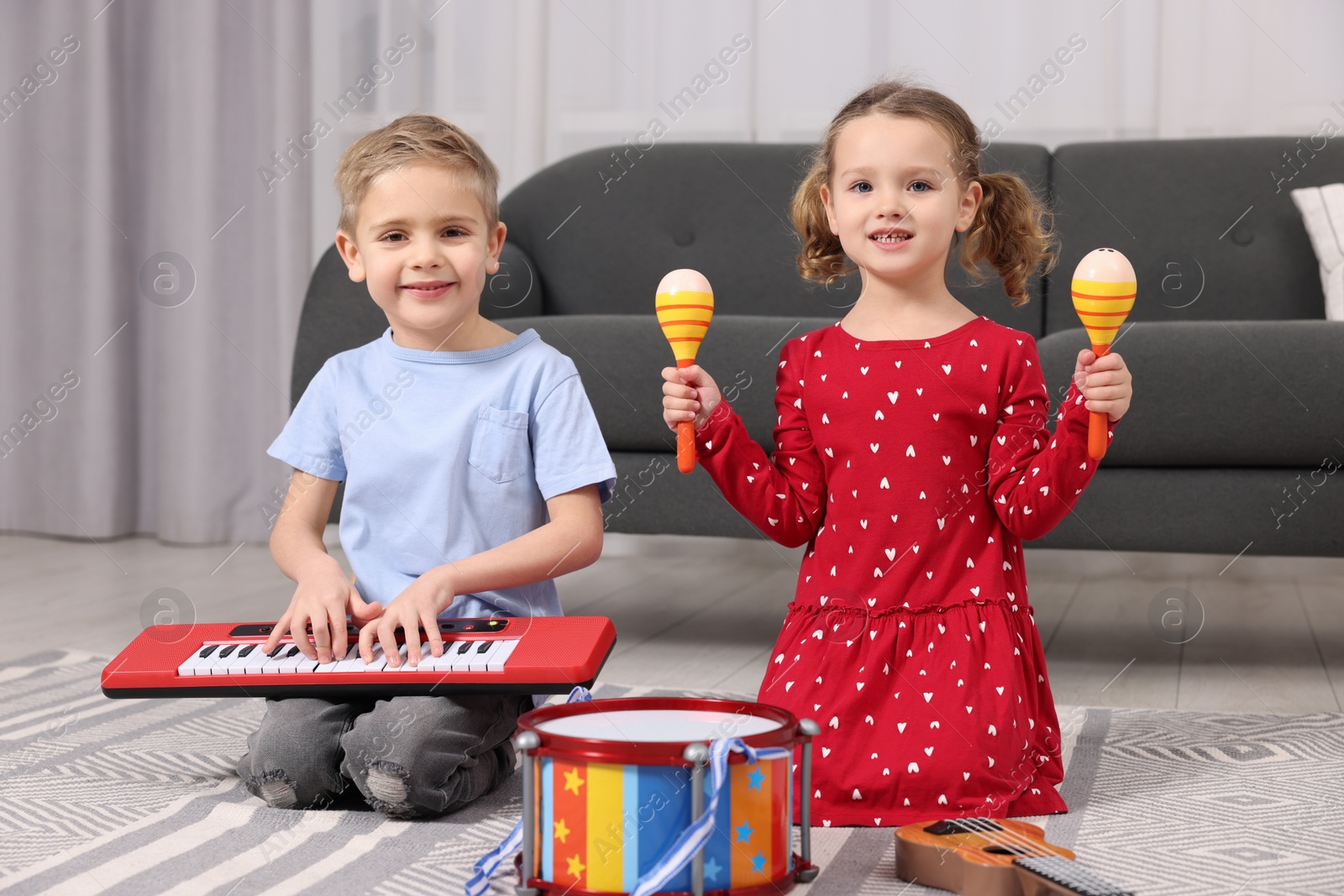 Photo of Little children playing toy musical instruments at home