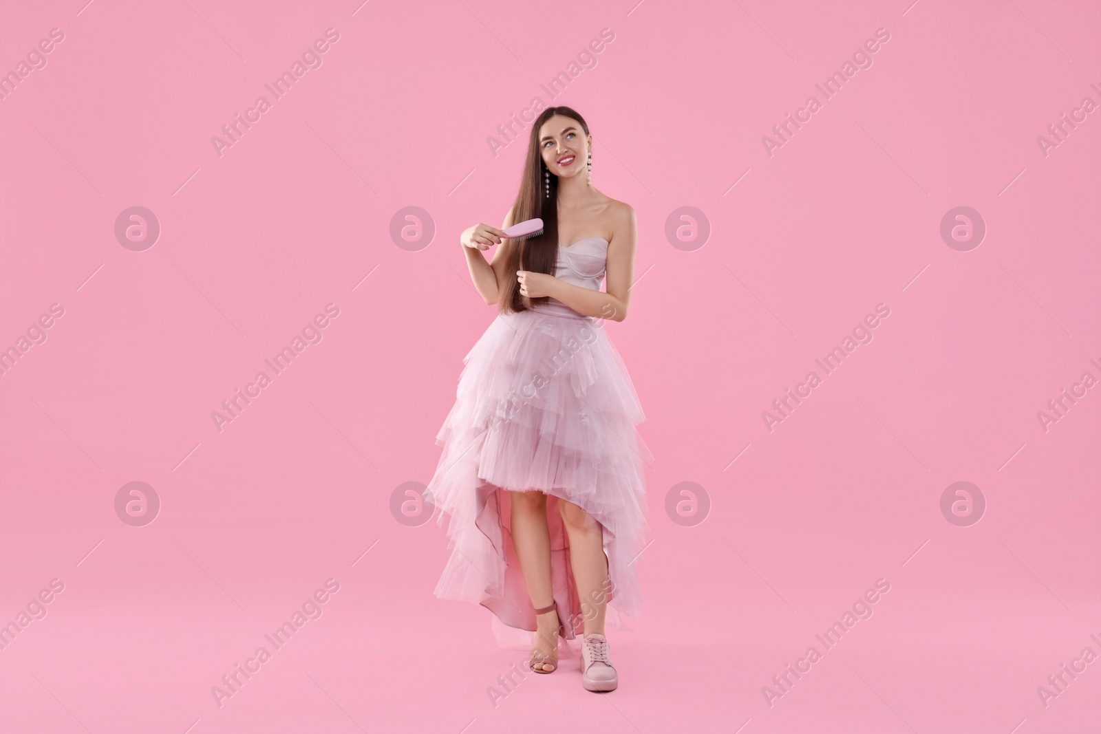 Photo of Woman wearing high heeled shoe and sneaker on pink background. Glamour vs comfort