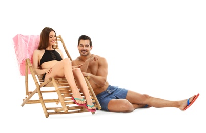 Young couple with sun lounger on white background. Beach accessories