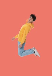 Image of Teenage boy jumping on coral background, full length portrait