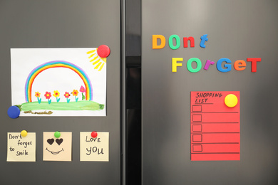 Modern refrigerator with child's drawing, notes and magnets