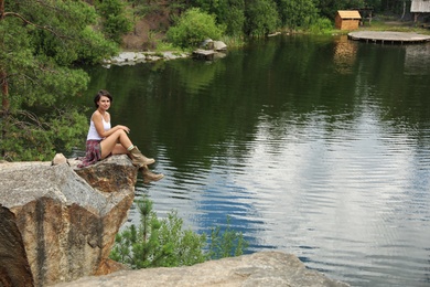 Young woman on rocky mountain near lake. Camping season