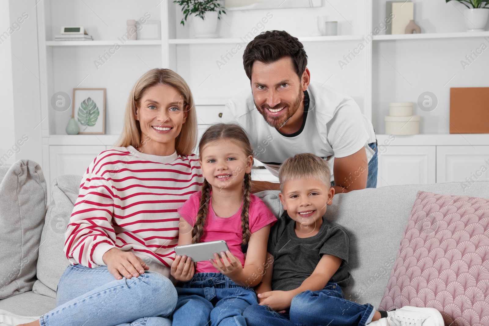 Photo of Happy family with smartphone spending time together on sofa at home