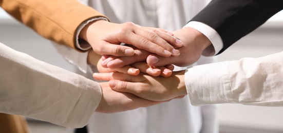 Image of Business partners. Group of people holding hands together in office, closeup. Banner design