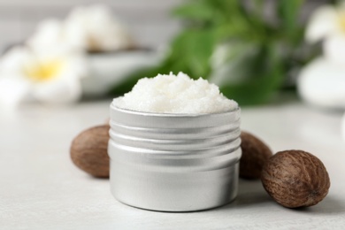 Photo of Shea butter in jar and nuts on white table, closeup