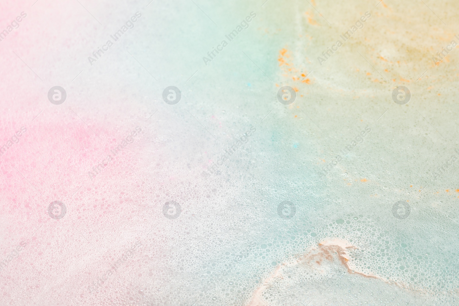 Photo of Colorful foam after dissolving bath bomb in water, closeup