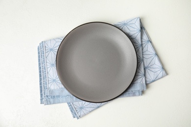 Photo of Empty plate and napkin on white table, top view