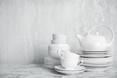 Photo of Set of clean tableware on white marble table. Space for text