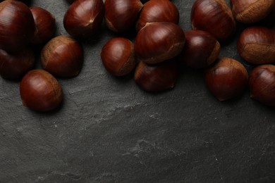 Photo of Roasted edible sweet chestnuts on grey textured table, flat lay. Space for text