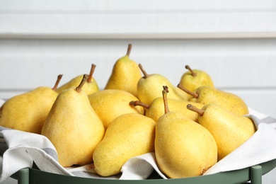 Tray with fresh ripe pears against light background