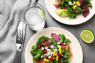 Photo of Tasty fresh kale salad on grey table, above view