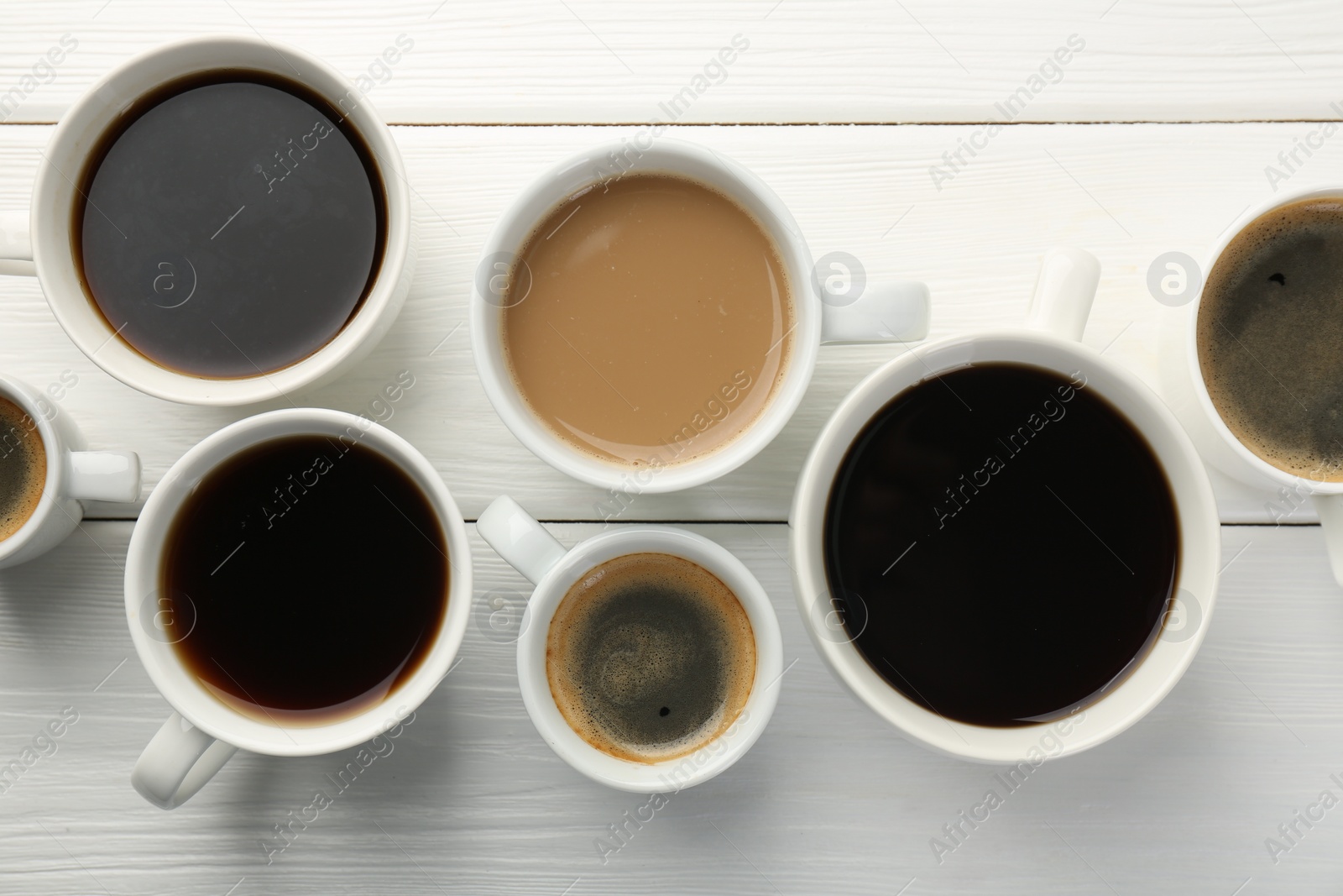 Photo of Different coffee drinks in cups on white wooden table, flat lay