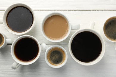 Photo of Different coffee drinks in cups on white wooden table, flat lay