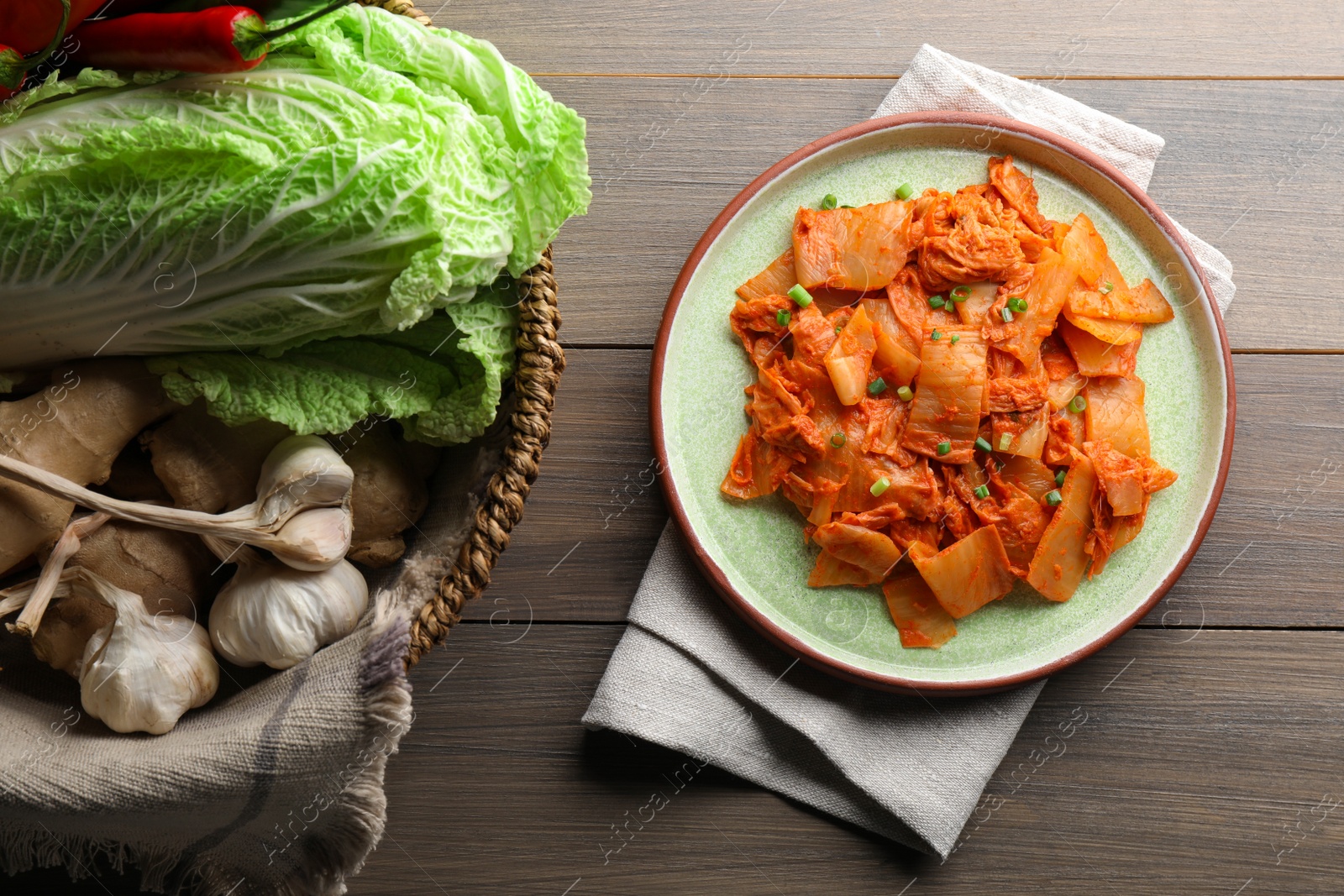 Photo of Delicious kimchi with Chinese cabbage and ingredients on wooden table, flat lay