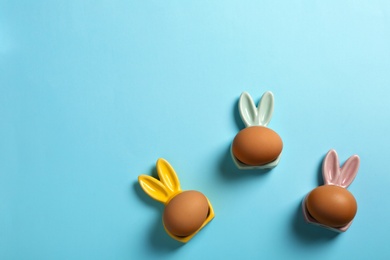 Photo of Flat lay composition of Easter bunny ears and eggs on color background, space for text