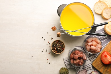 Photo of Flat lay composition with oil pot, meat fondue ingredients and space for text on light background