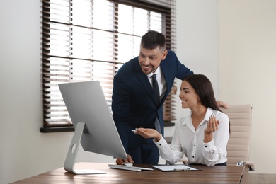 Photo of Man helping his colleague with work in office