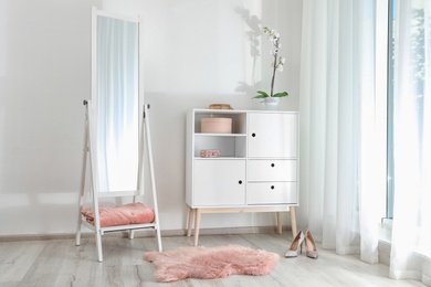 Photo of Stylish living room interior with chest of drawers and mirror