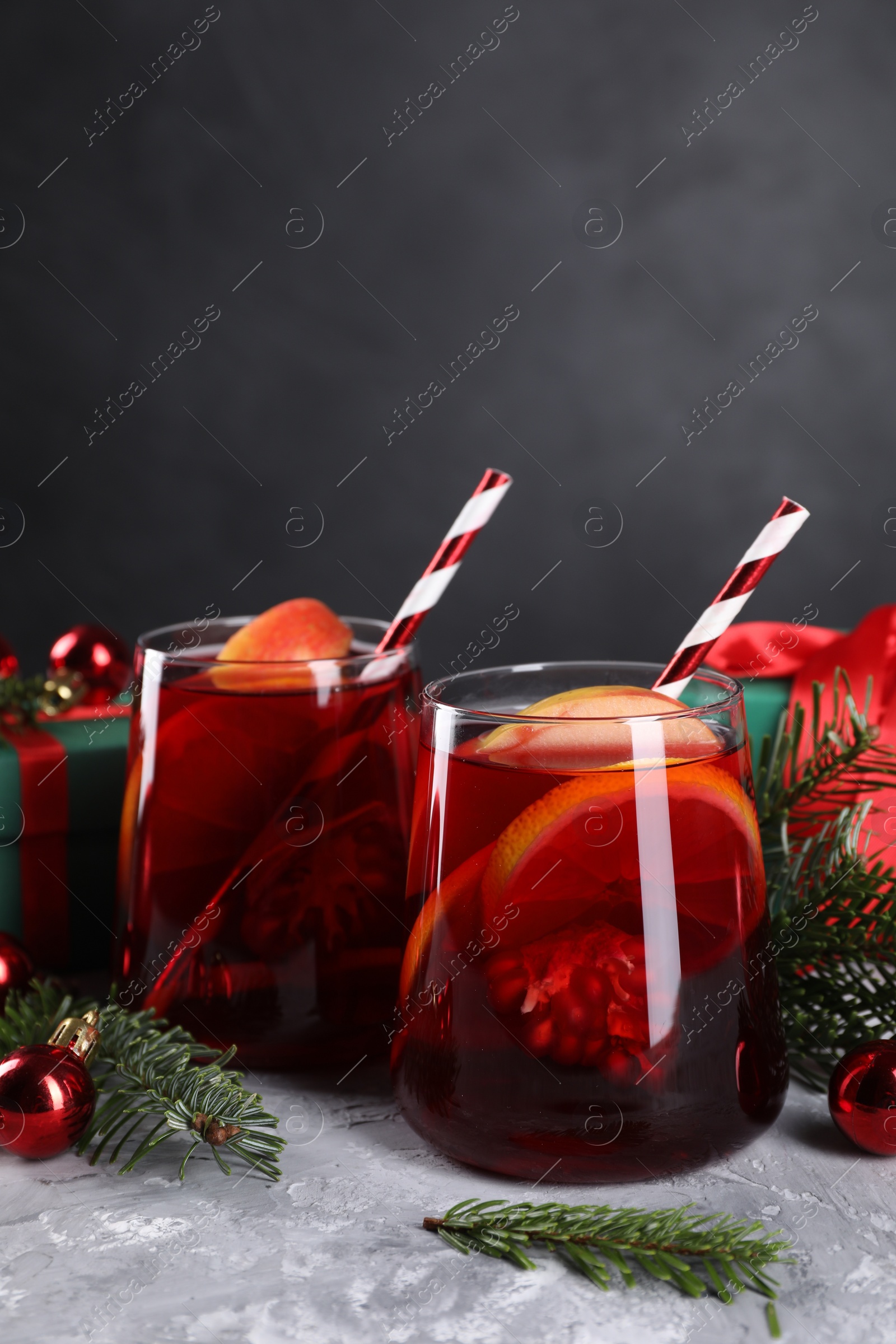 Photo of Delicious Sangria drink in glasses and Christmas decorations on grey textured table, closeup