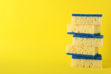 Stacked cleaning sponges on yellow background. Space for text