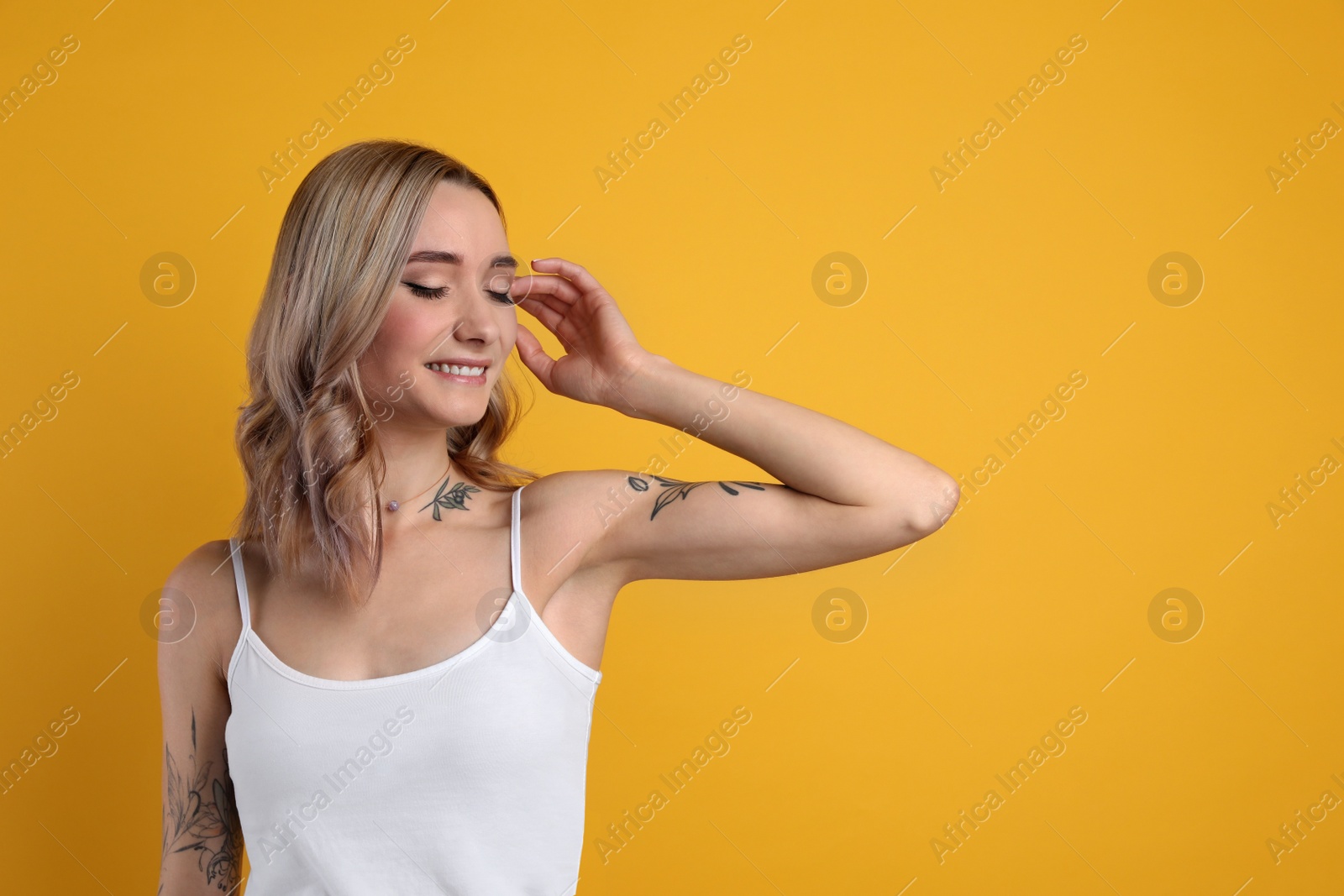 Photo of Beautiful woman with tattoos on body against yellow background