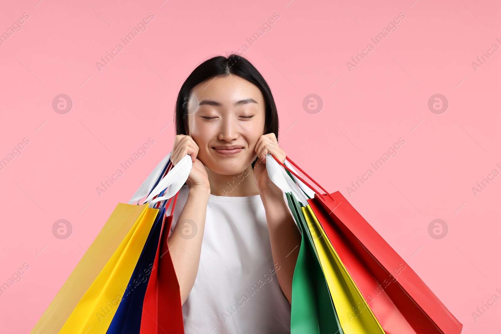 Photo of Happy woman with shopping bags on pink background