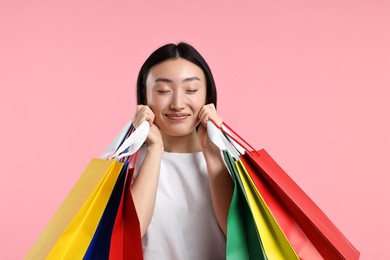 Happy woman with shopping bags on pink background