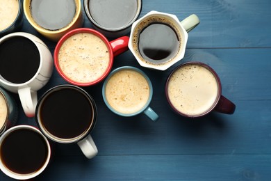 Many cups of different coffee drinks on blue wooden table, flat lay