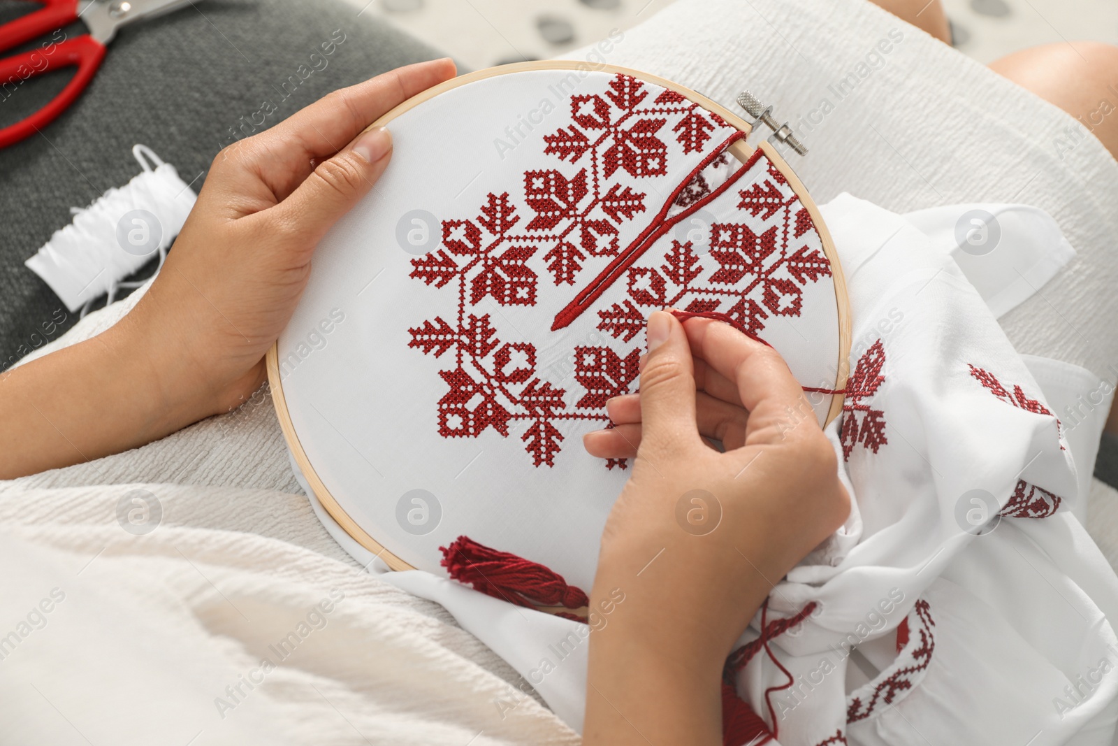 Photo of Woman embroidering white shirt with colorful threads in hoop, above view. Ukrainian national clothes