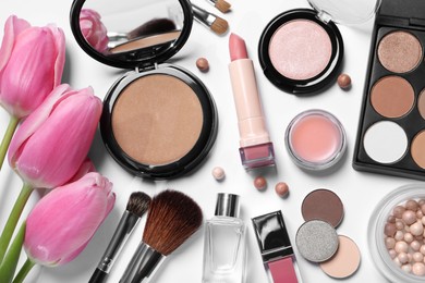 Photo of Flat lay composition with different makeup products and beautiful tulips on white background