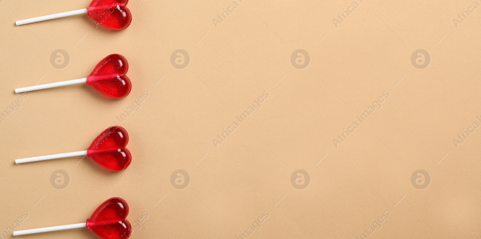 Photo of Sweet heart shaped lollipops on beige background, flat lay with space for text. Valentine's day celebration