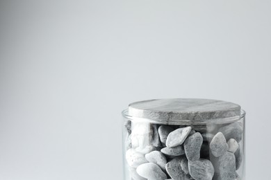 Photo of Presentation for product. Glass container with stones on light grey background. Space for text