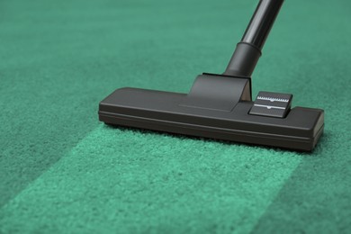 Image of Vacuuming dirty green carpet. Clean area after using device, closeup