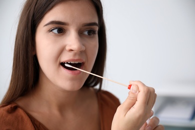 Woman taking sample for DNA test indoors, closeup