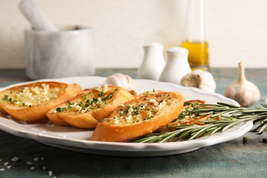 Plate with delicious homemade garlic bread on table