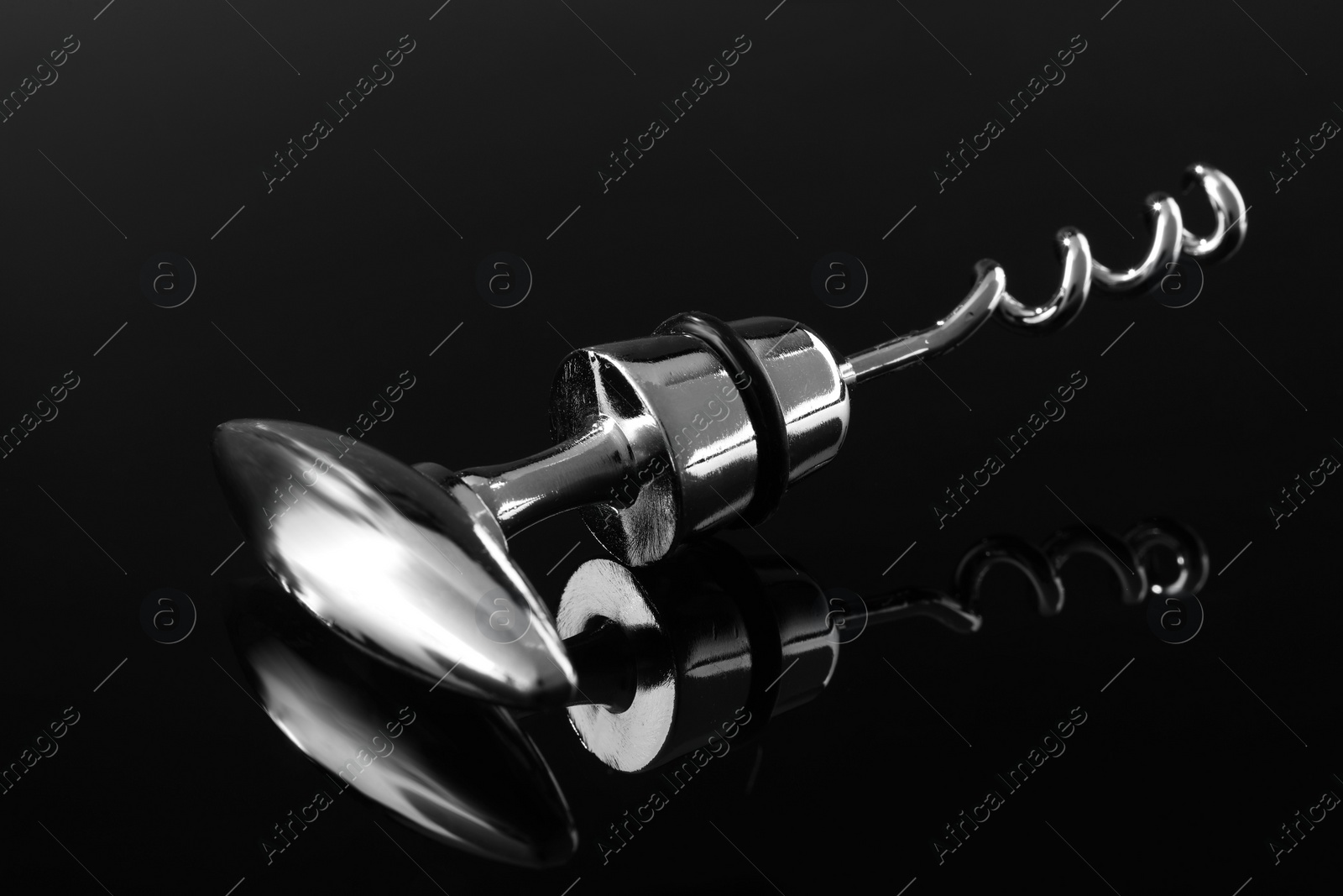 Photo of One metal corkscrew on dark mirror surface, closeup