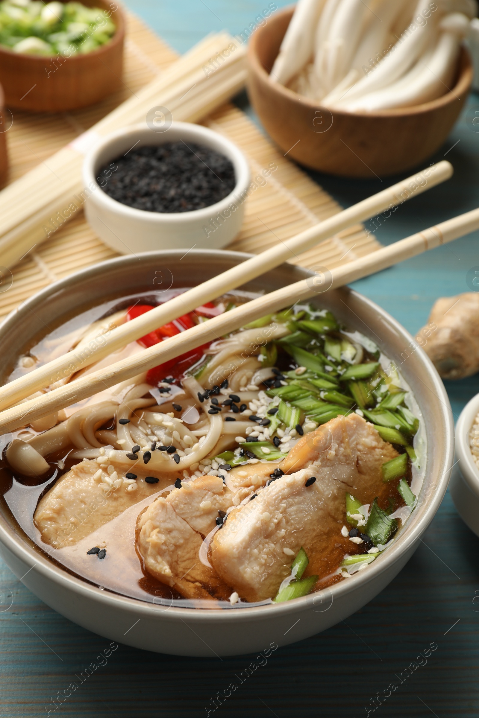 Photo of Delicious ramen with meat and ingredients on light blue wooden table. Noodle soup