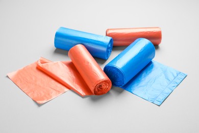 Photo of Rolls of different color garbage bags on light background