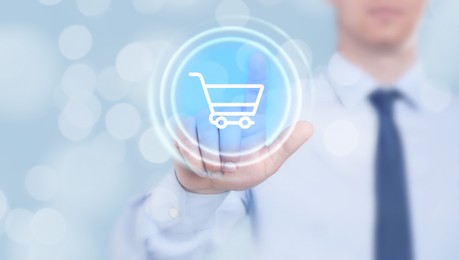 Image of Man pointing at icon of shopping cart on virtual screen, closeup. Online store