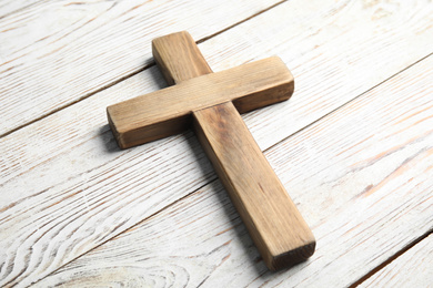 Photo of Christian cross on white wooden background, closeup. Religion concept