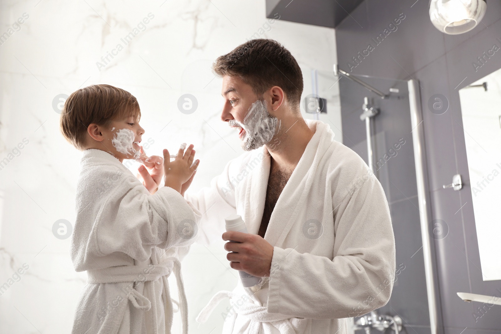 Photo of Dad applying shaving foam onto son's face in bathroom